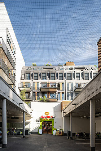 Wejście z miejscami parkingowymi dla marketu Alnatura znajduje się na wewnętrznym dziedzińcu dzielnicy mieszkalnej.