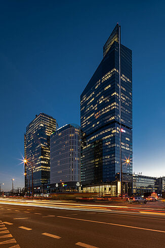 Podświetlony Skyliner Tower w Warszawie nocą.