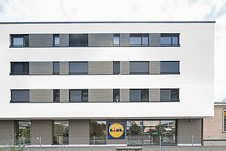 Front view of a mixed-use building with a Lidl supermarket and flats above.