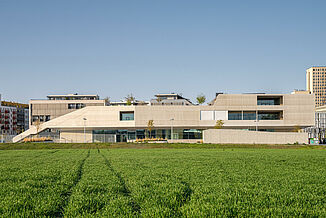 Widok z zewnątrz na nowoczesny kompleks budynków kampusu edukacyjnego Seestadt Aspern w Wiedniu.