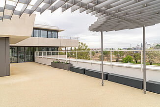 One of the many roof terraces of the Aaron Mencer Campus in Vienna with a view of the greenery.