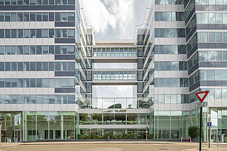 Wejście do budynku wielofunkcyjnego West Plaza ze szklaną fasadą.