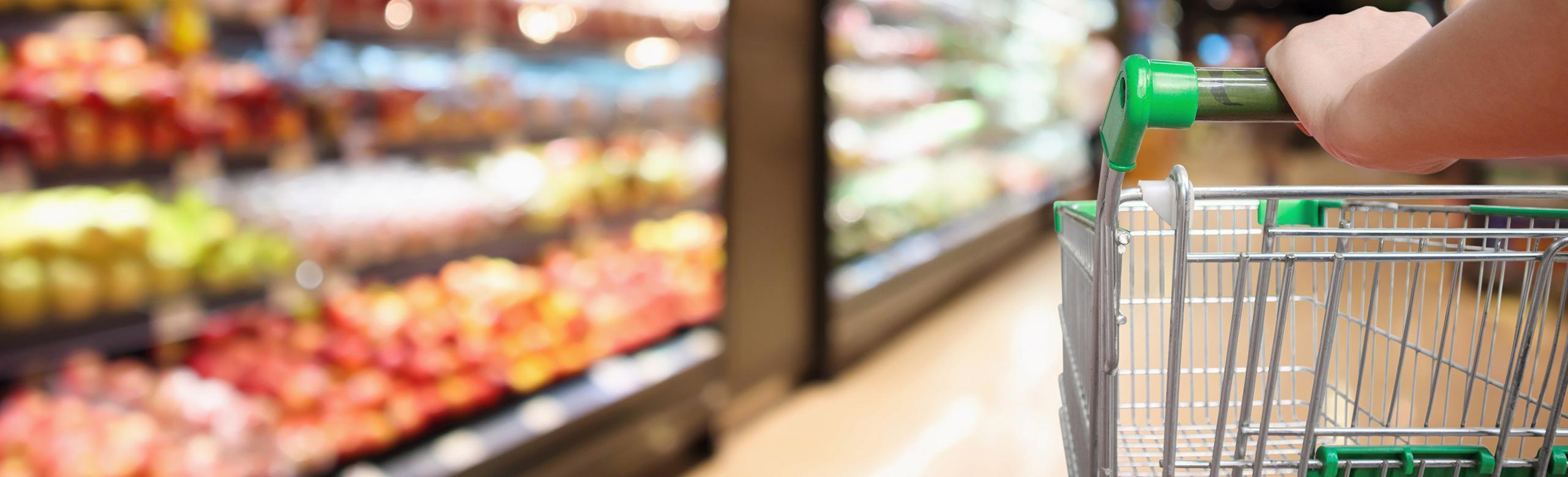 A shopping trolley is pushed through a supermarket.